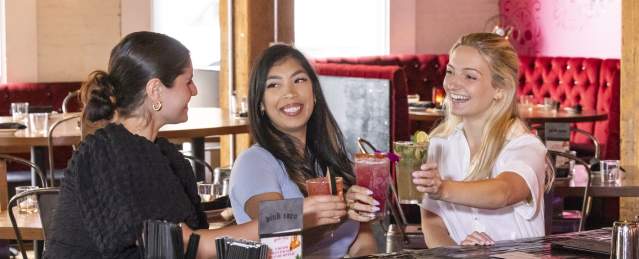 3 women smiling with cocktails. girls night