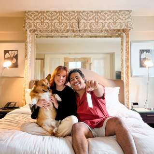 Couple with dog on hotel bed