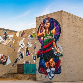 Mural depicting child wearing a dress reading Roxbury blowing bubbles and surrounded by blowing posters and books