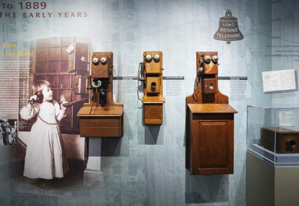Antique photo of a girl holding an old wooden telephone